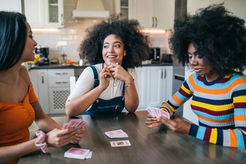 trys merginos namuose lošia kortomis