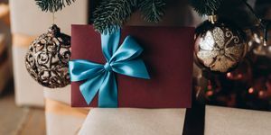 dovanų kuponas bordo spalvos voke su mėlynu lankeliu po eglute kalėdinė dovana